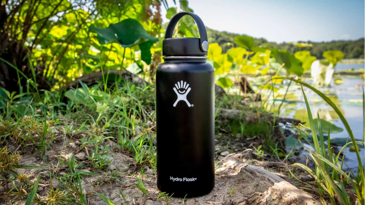 Black Hydro Flask sits on a shore