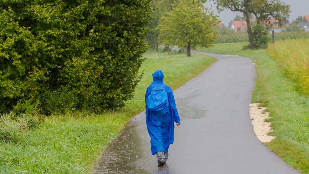A woman wearing a blue poncho walking in the rain