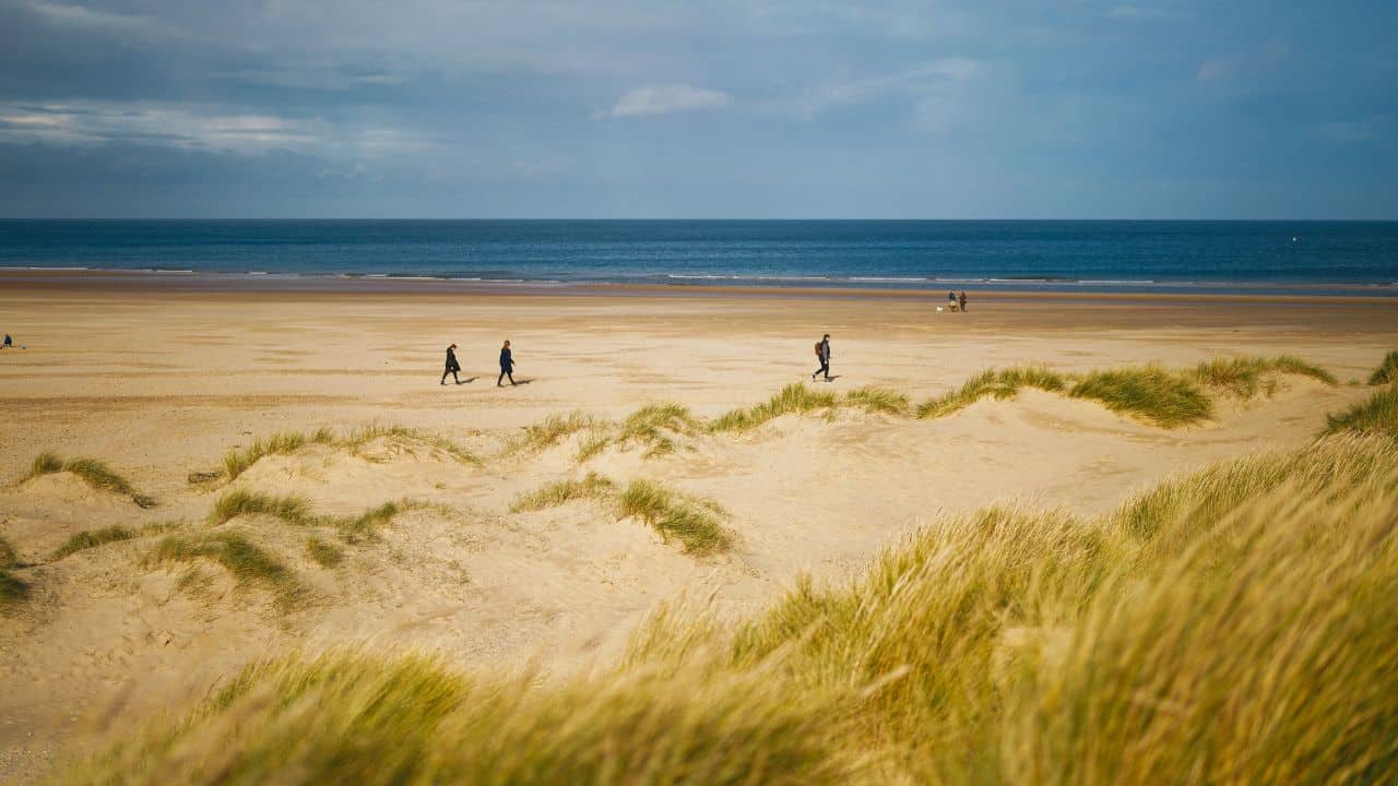Hikers walking on a sandy beach in Norfolk
