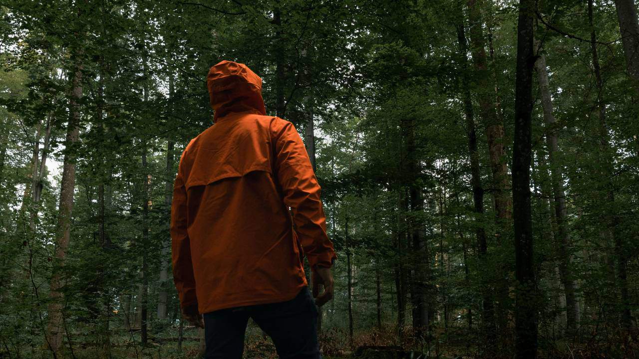 Man wearing a red jackets walking in the woods