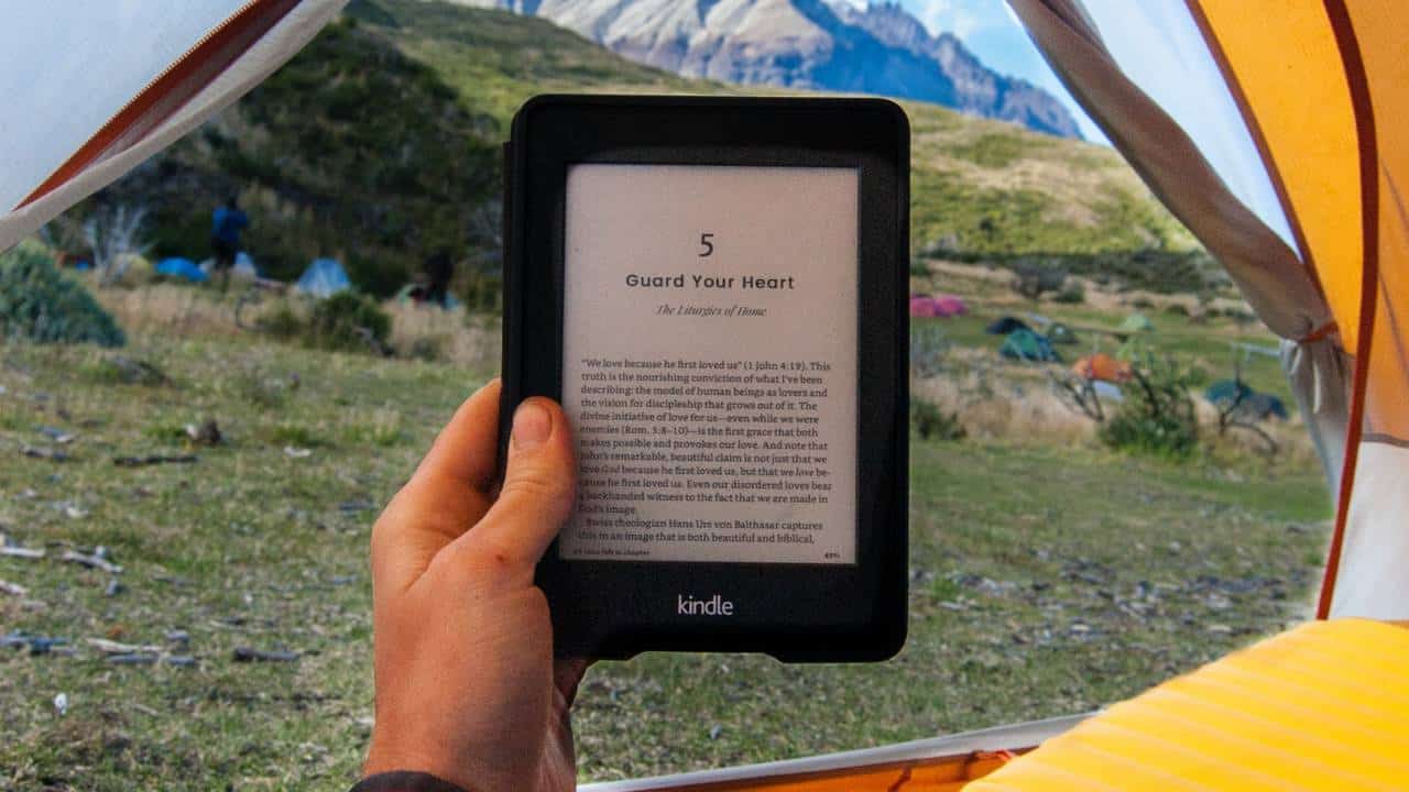 Camper holding a kindle in a tent