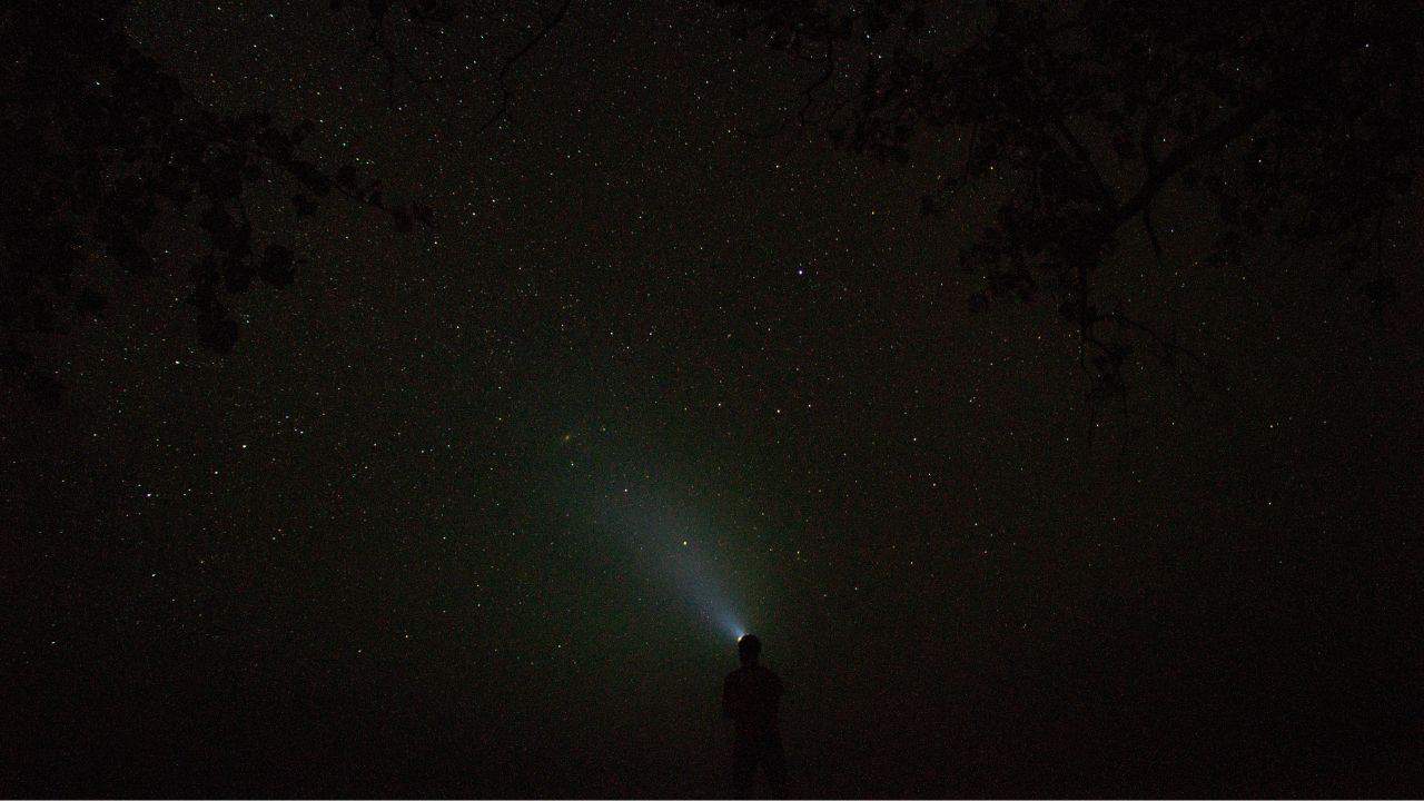 Camper wearing a head torch and looking at the sky