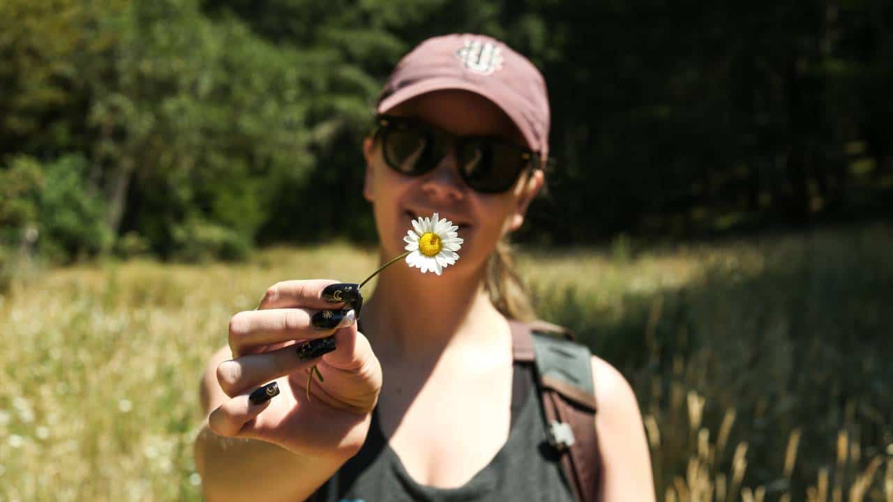 Camper with black glasses and black nails holding a flower