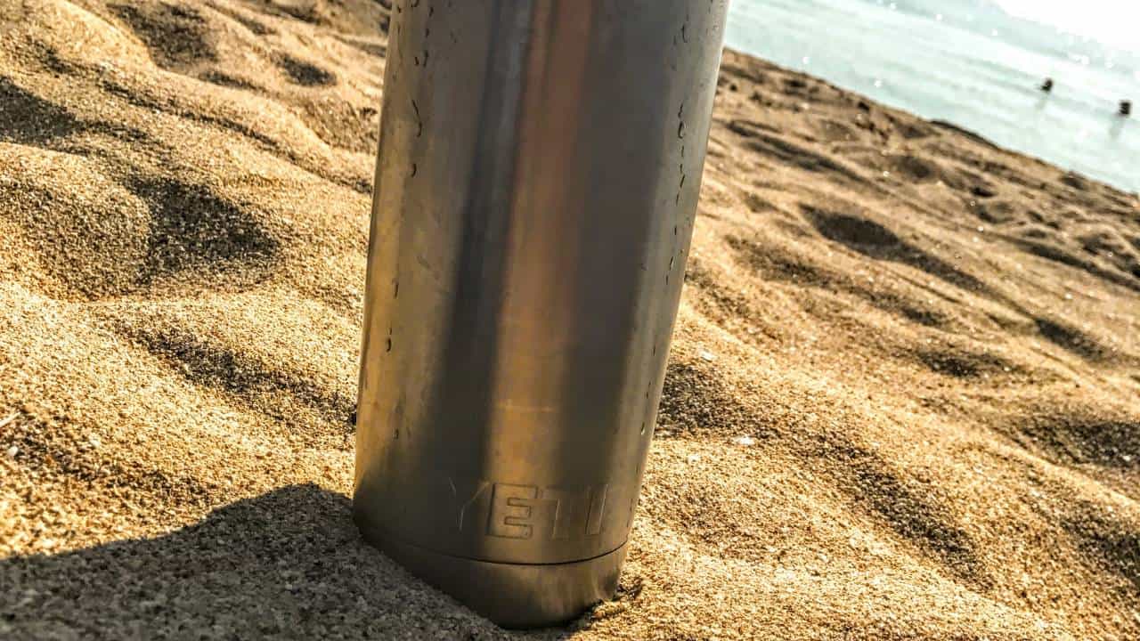 A photo of a silver Yeti bottle in a beach setting